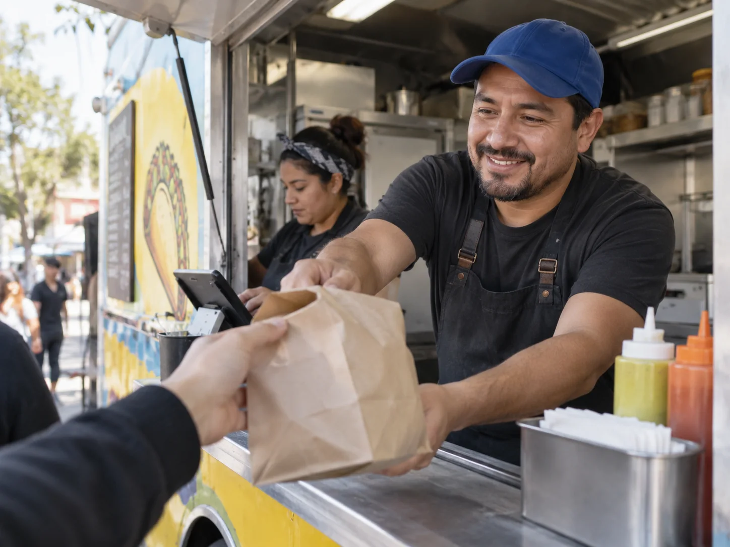A food-truck owner hands a takeaway order to a customer.
