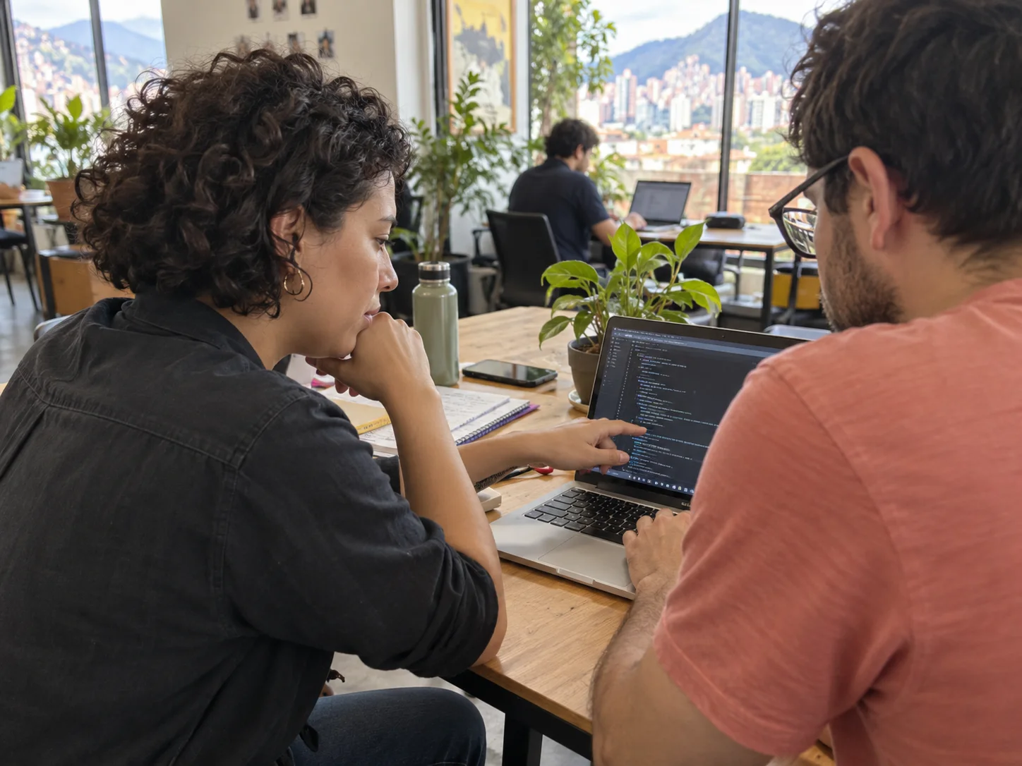 Two developers work on a laptop in a neighborhood coworking space.