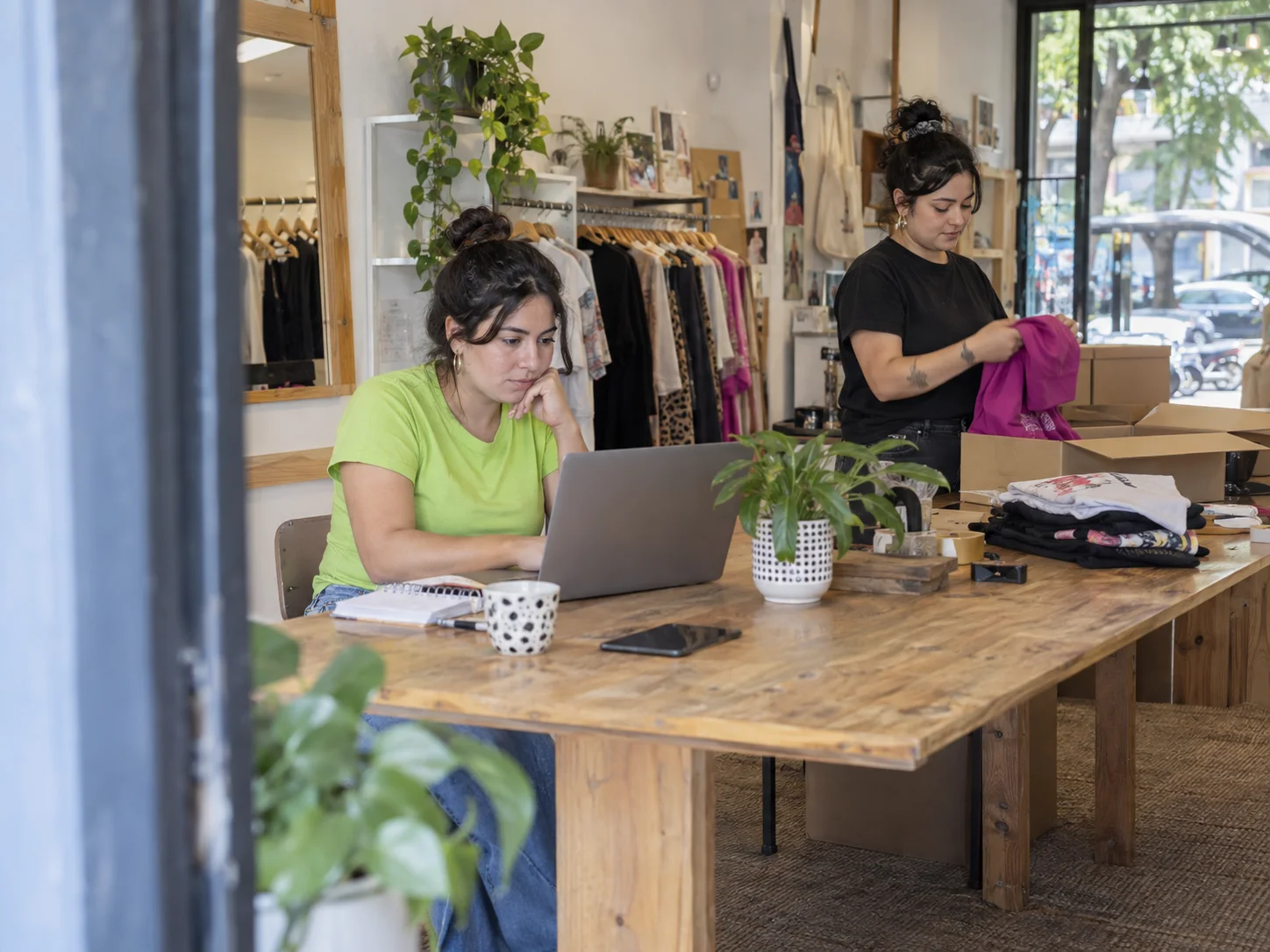 A small clothing brand owner checks an online order while packing it.